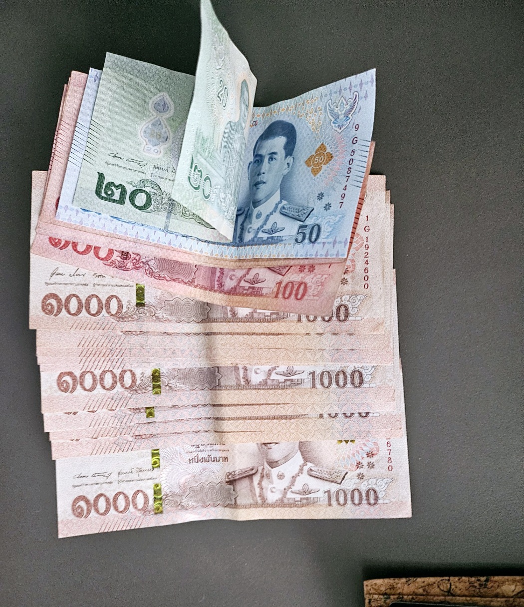 1000바트 지폐 여러 장과 함께 100바트, 50바트, 20바트까지 다양한 태국 바트 화폐 단위가 정리된 실제 사진