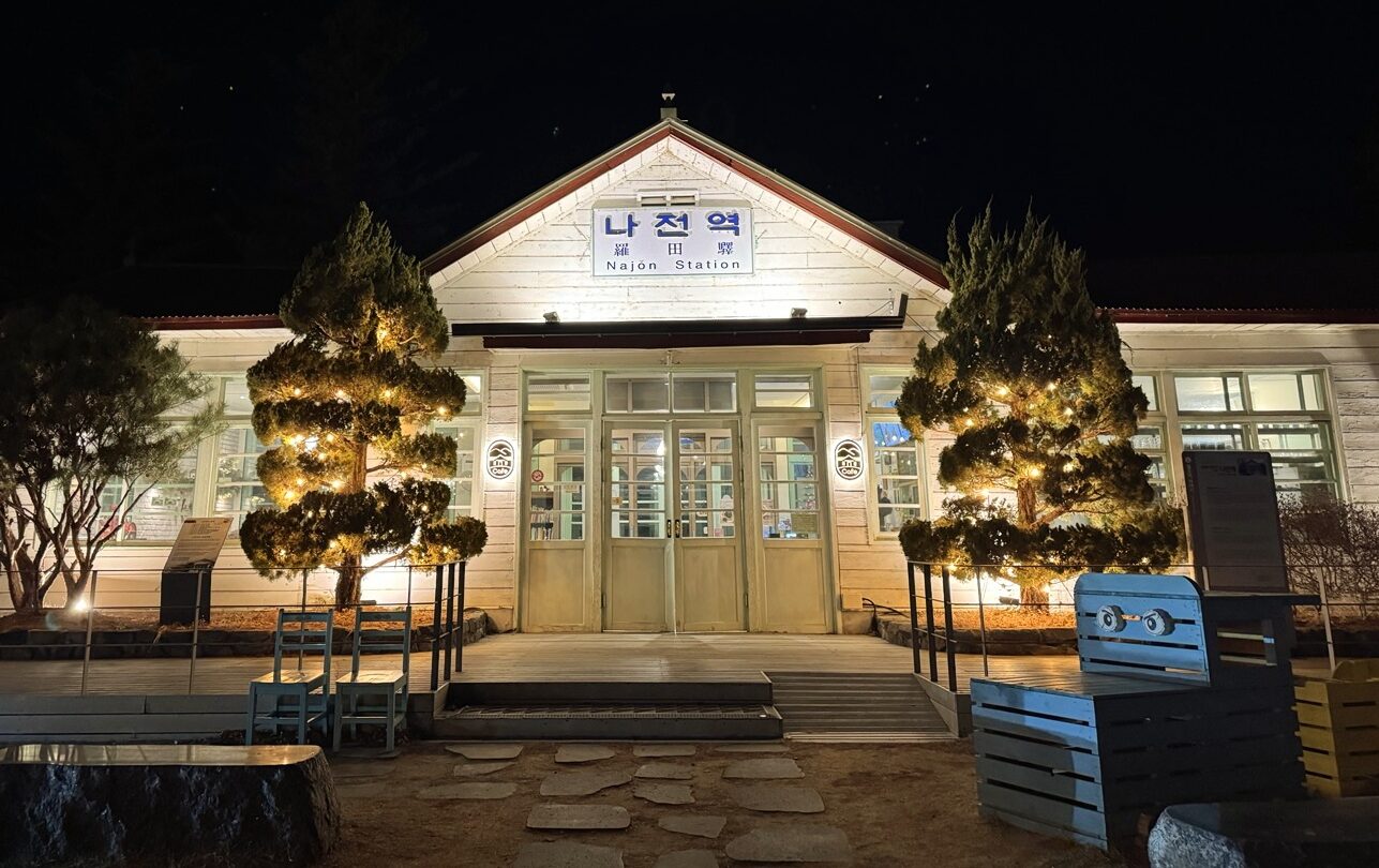정선 가볼만한 곳 정선 나전역의 야간 전경. 조명이 켜진 간이역 건물이 운치 있게 서 있으며, 뉴트로한 감성이 느껴진다.