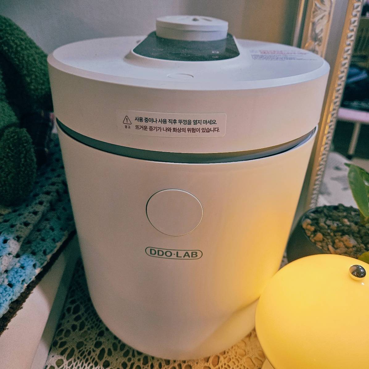 따뜻한 조명과 어우러진 디디오랩 DHF-L55SW 가열식 가습기의 실제 사용 장면. 감성적인 인테리어에 잘 어울리는 미니멀 디자인이 돋보인다.